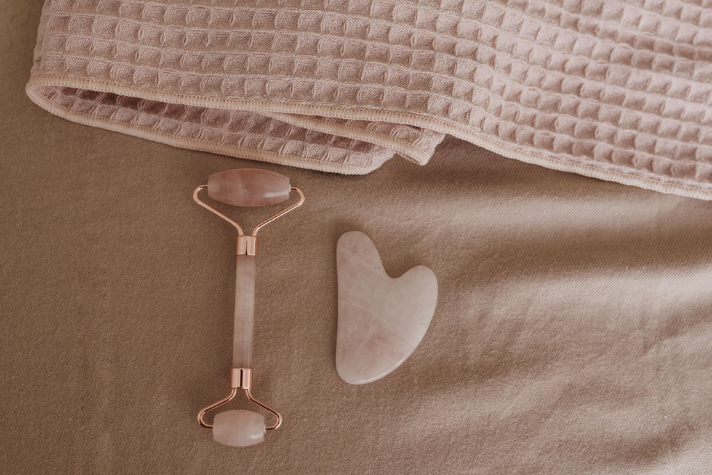 Rose quartz facial roller and gua sha set on soft pink towel