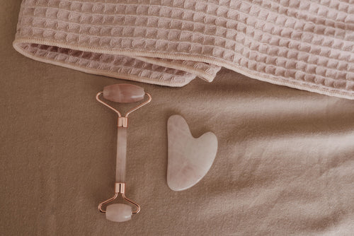 Rose quartz facial roller and gua sha set on soft pink towel