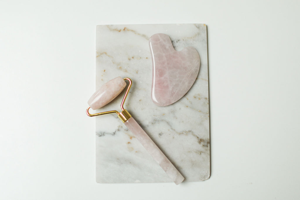 Sielvane rose quartz facial roller and gua sha stone flat lay on marble