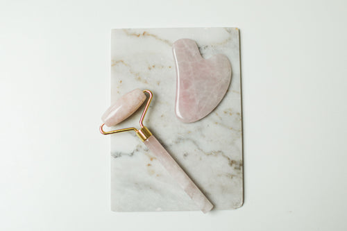 Sielvane rose quartz facial roller and gua sha stone flat lay on marble